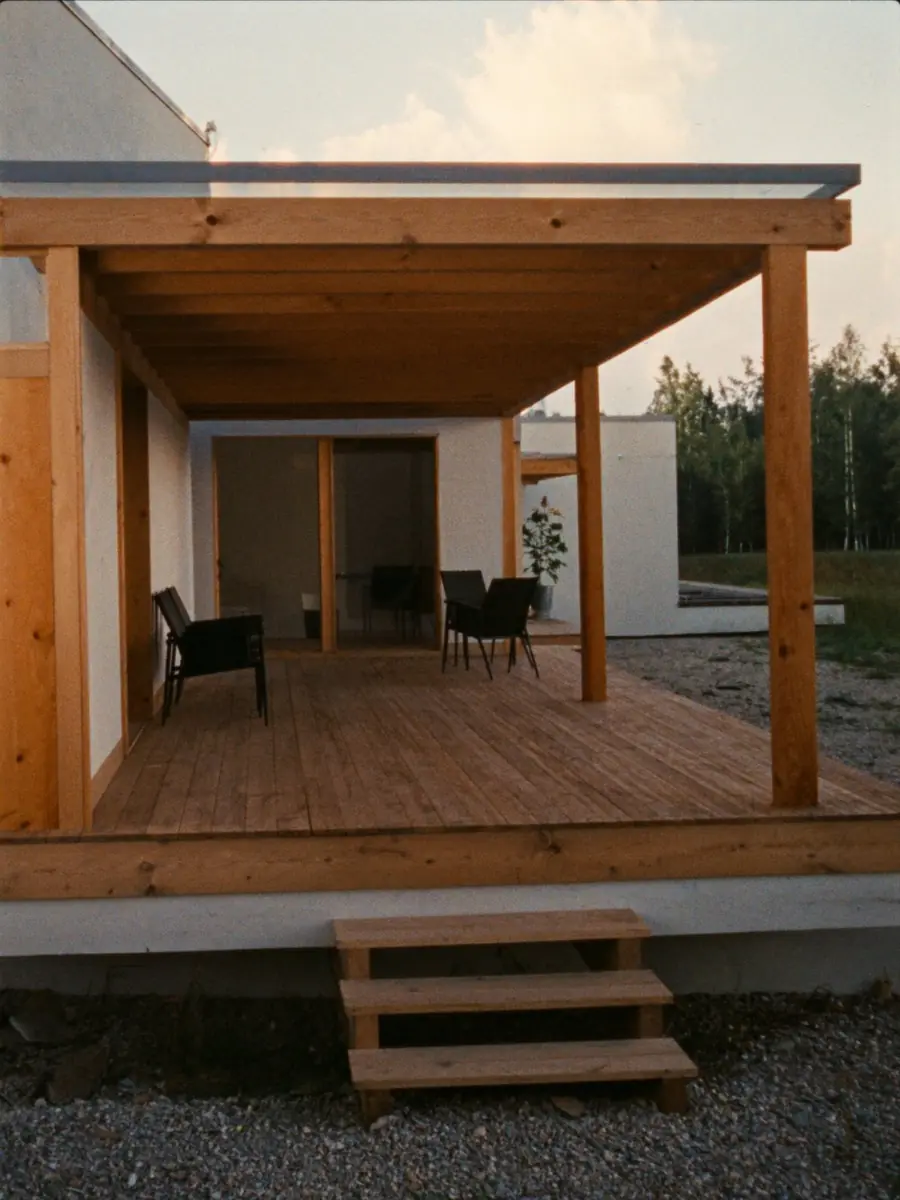 Terrasse i furu med overbygg på stolper og en kort trapp ned til grusen