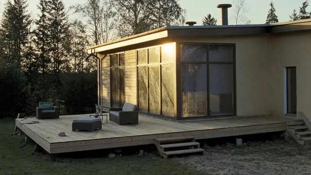 Lav terrasse rundt et hus med flatt tak, med to trapper ned til hagen